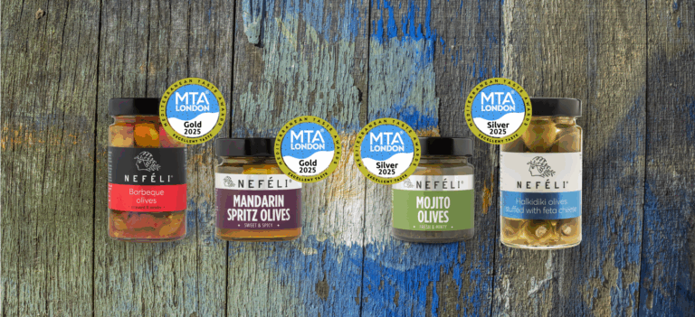 Award-winning Nefeli olive products on rustic wood background, featuring Barbeque, Mandarin Spritz, Mojito, and Feta-Stuffed Halkidiki Olives with MTA London 2025 medals